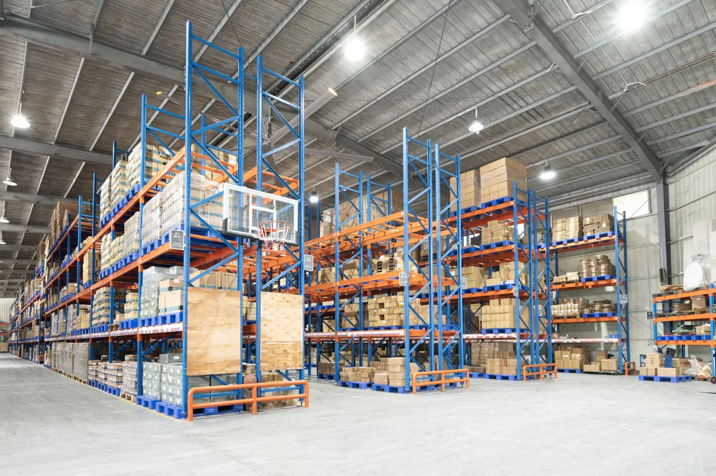 Pallet racks and stacked cartons in a bright high-ceiling warehouse