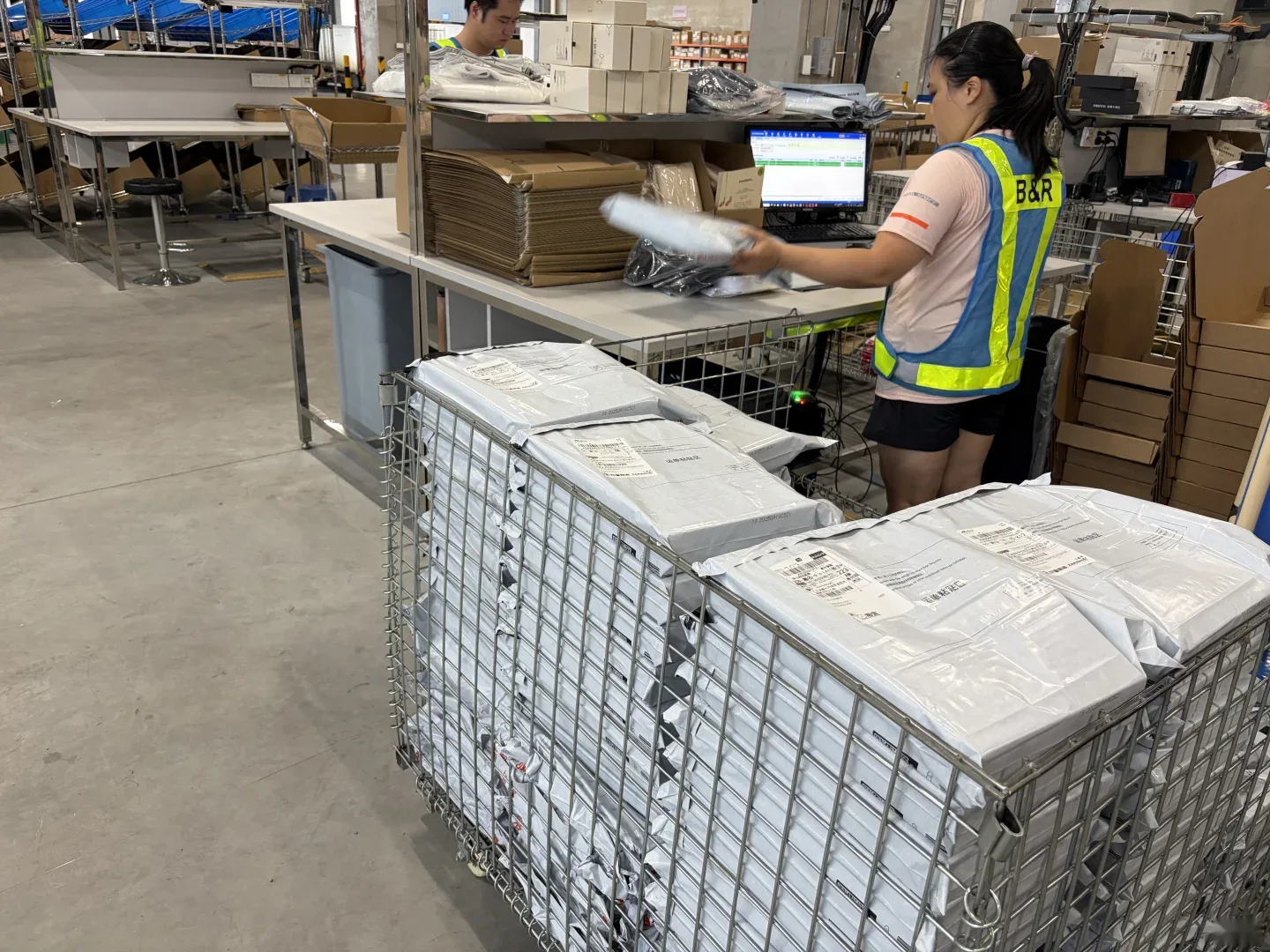 Warehouse operator beside a wire cage and parcel processing equipment