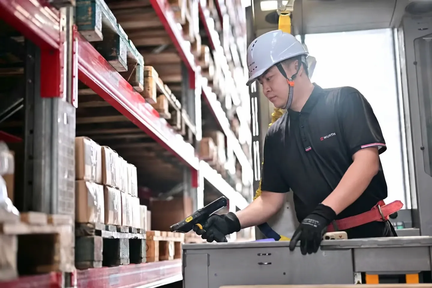 Warehouse worker scanning goods beside a red storage rack