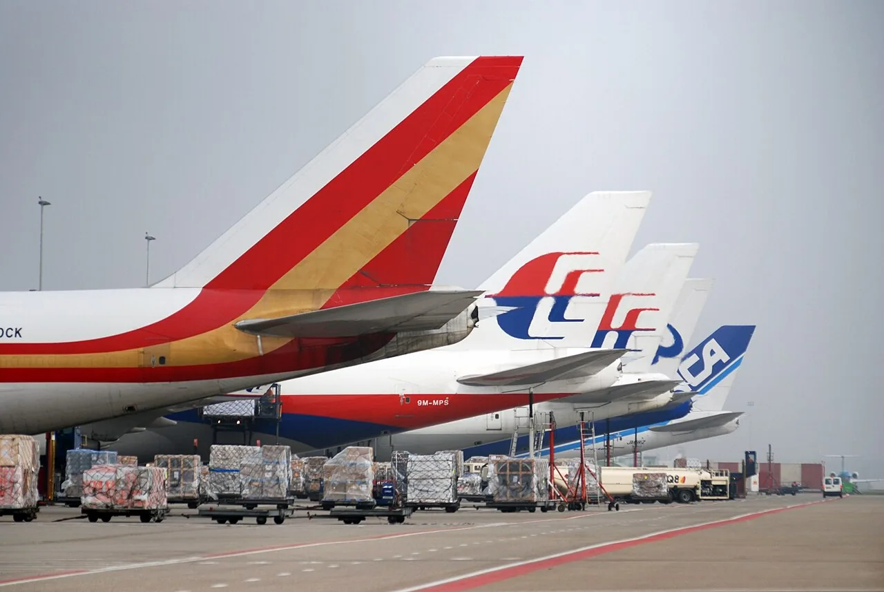 A row of cargo aircraft tails and handling equipment on the apron