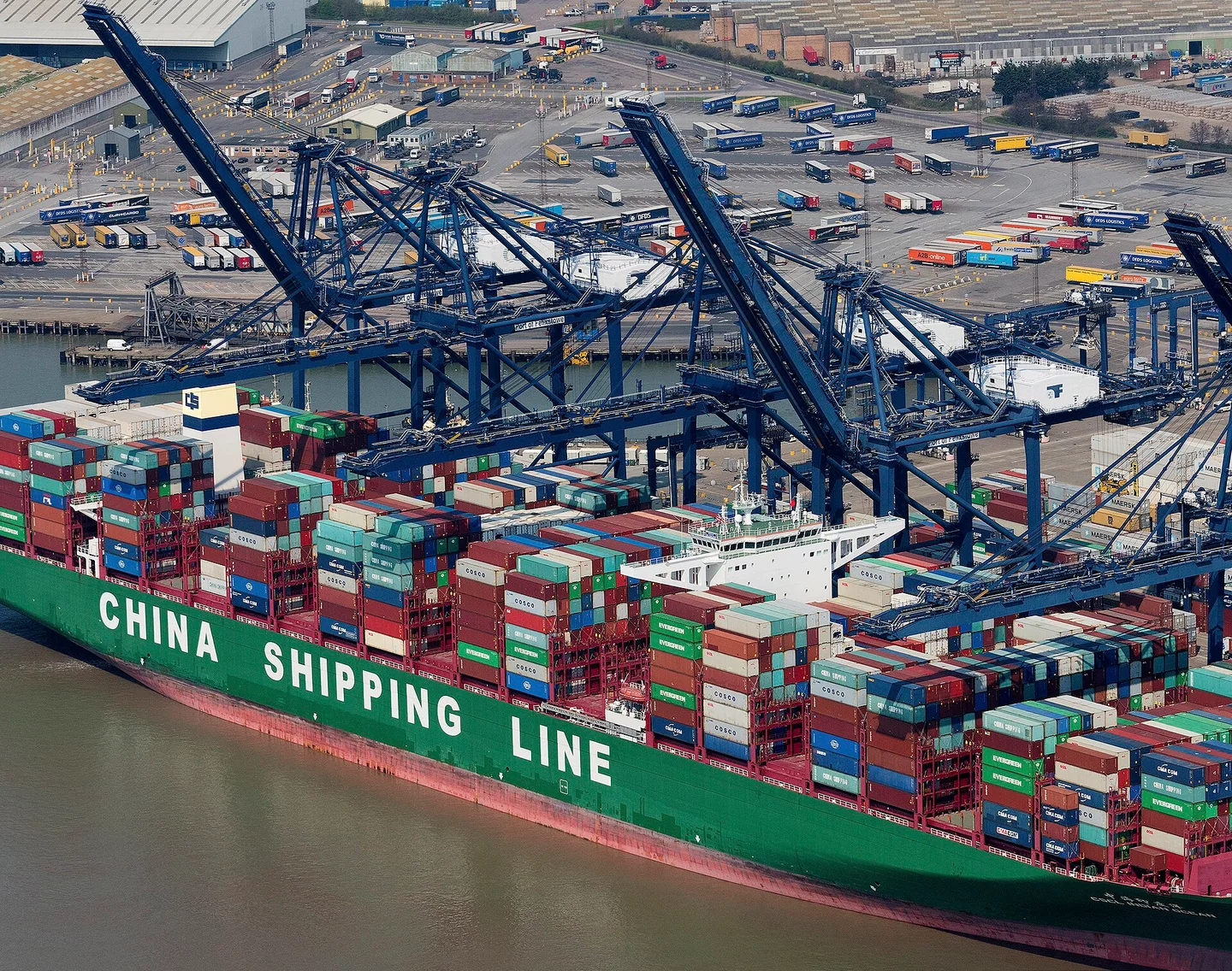 Container cranes working alongside a densely loaded container ship