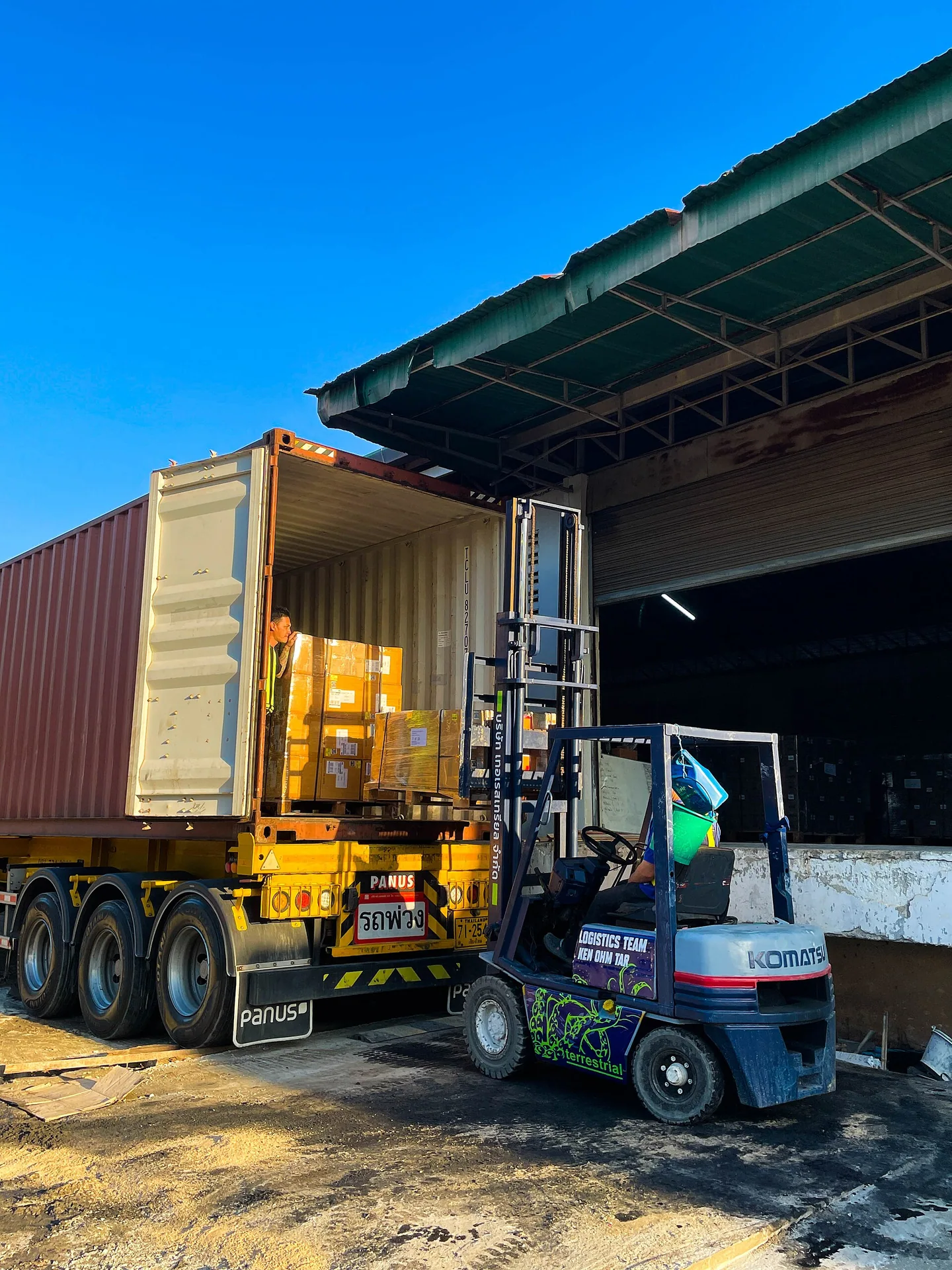 Forklift beside an open shipping container at a warehouse loading bay