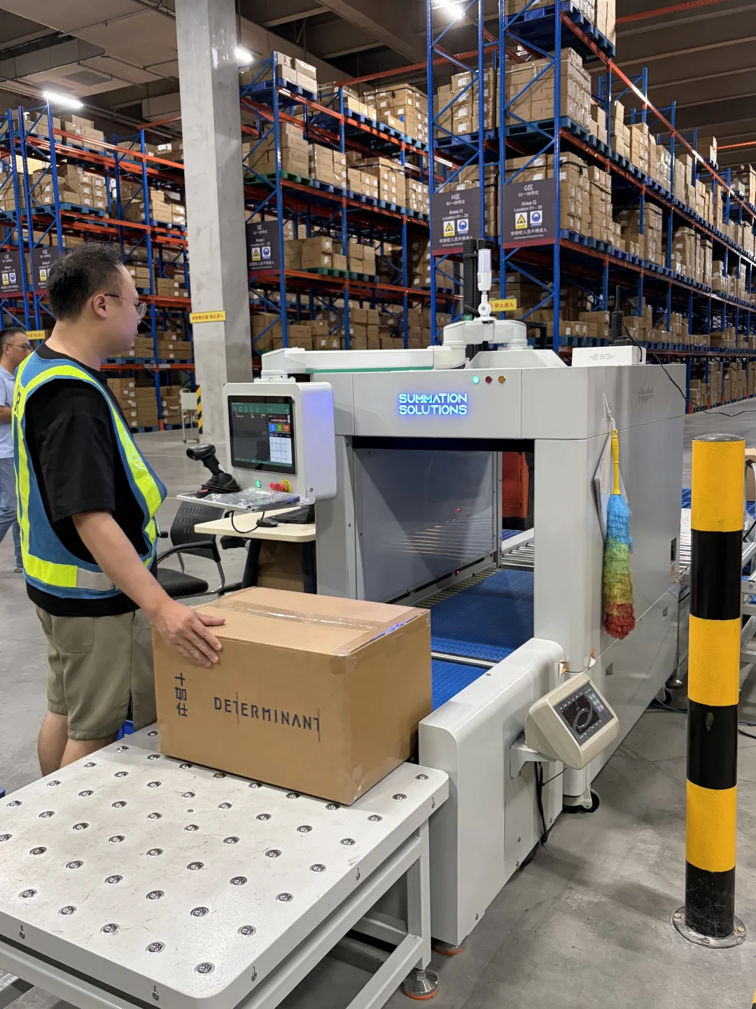 Worker feeding a carton into a warehouse processing station