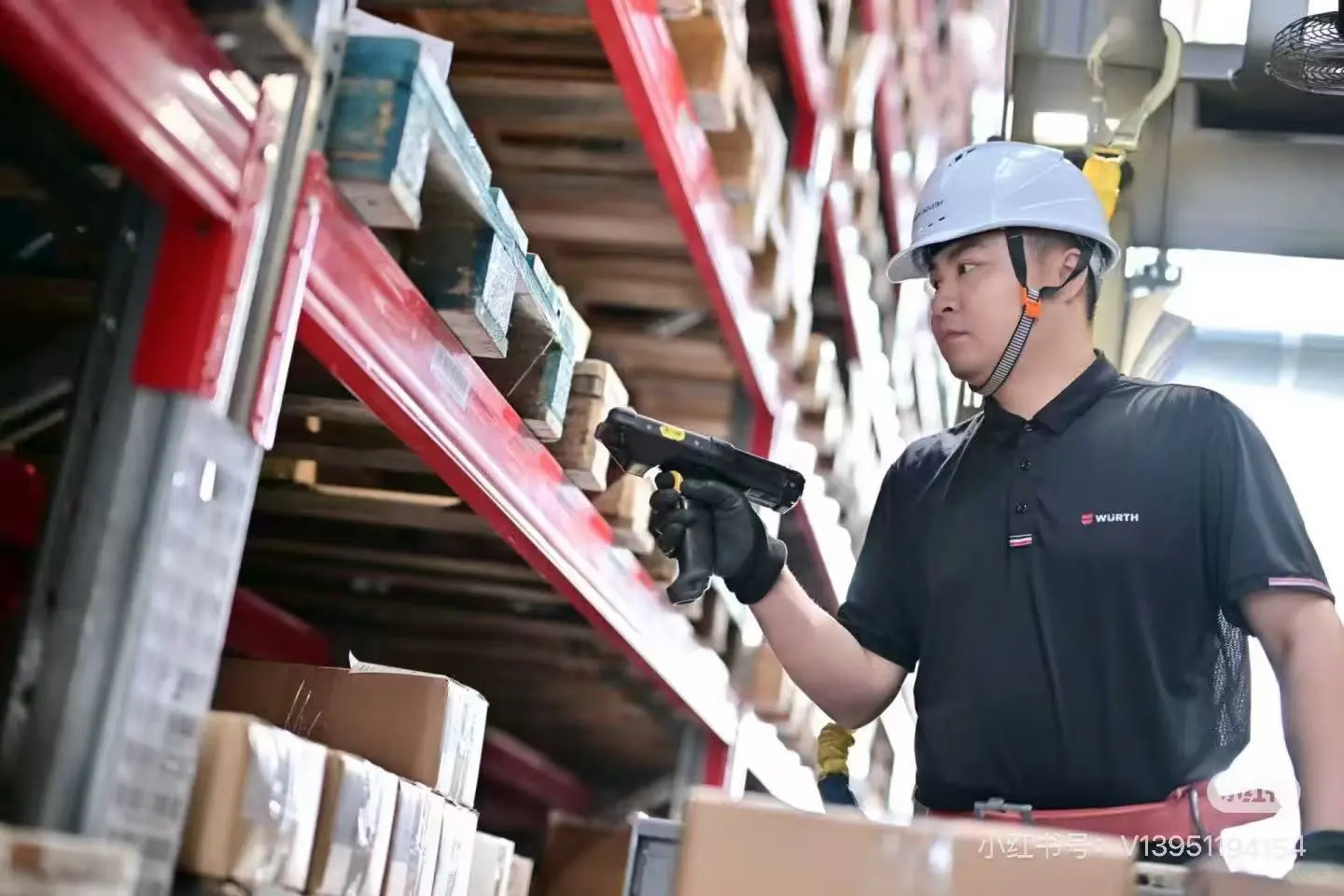 Warehouse operator checking stock beside red pallet racks