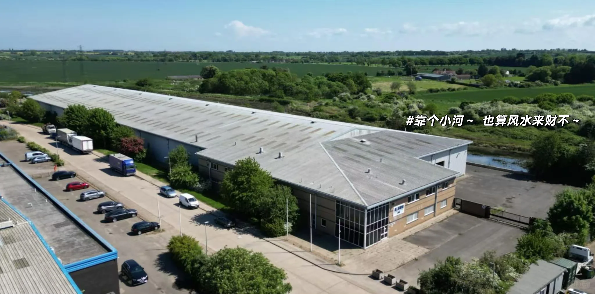 Wide aerial view of a logistics warehouse surrounded by roads and greenery
