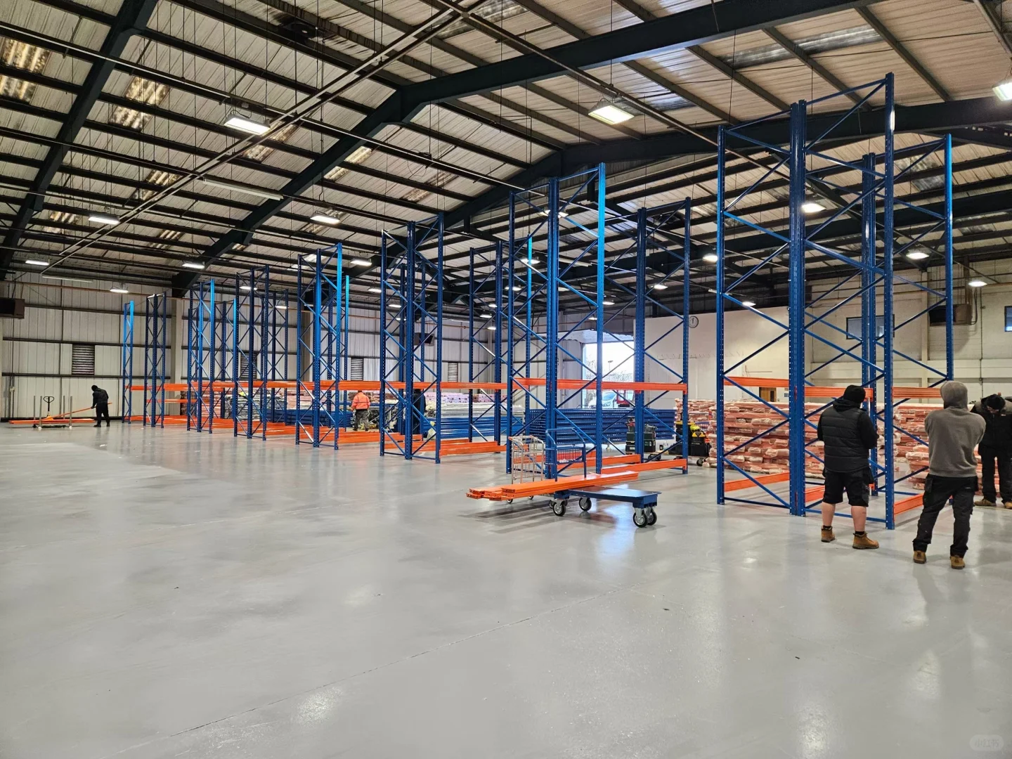 Open warehouse hall with blue and orange racks being installed