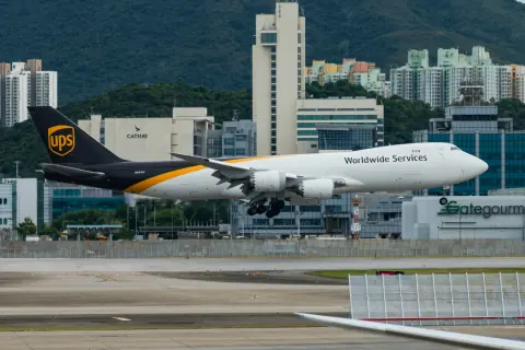 UPS cargo aircraft on a taxiway against a mountain and city backdrop