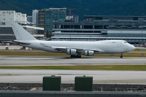 Cargo aircraft on an airport taxiway beside terminal buildings