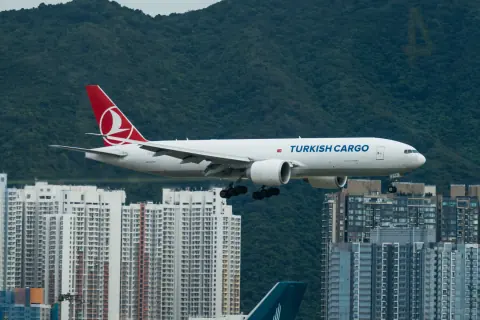 Turkish Cargo aircraft above an airport with a dense city backdrop