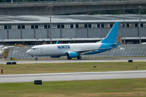 Blue and white cargo aircraft passing a hangar on a taxiway