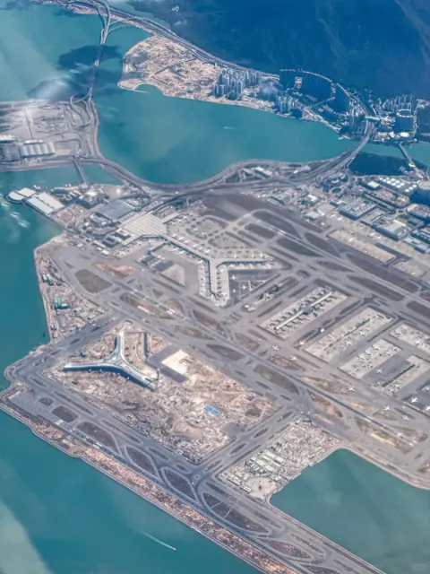 Aerial view of a coastal airport beside turquoise water