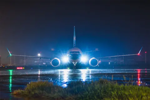 Aircraft facing the camera on a wet airport apron at night