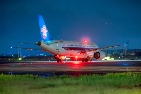 Passenger aircraft on a brightly lit airport apron at night