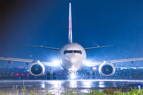 Head-on aircraft with bright lights reflecting across wet tarmac