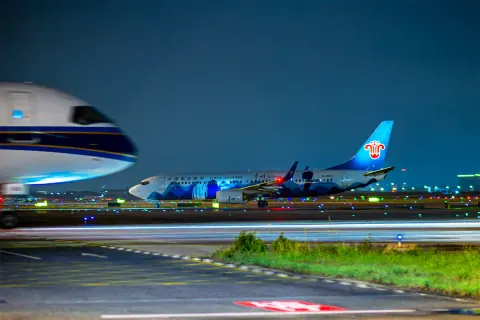 Parked aircraft and a ground vehicle under blue-hour airport lighting
