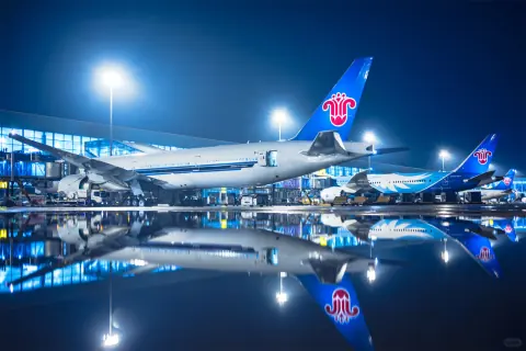 Parked aircraft and terminal lights reflected on a wet airport apron