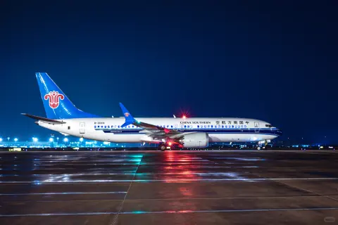 Two passenger aircraft and their reflections on a rain-soaked night apron