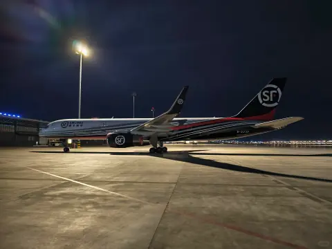 SF cargo aircraft parked under tall apron lights at night