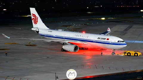 Passenger aircraft beside ground service vehicles on a lit night apron
