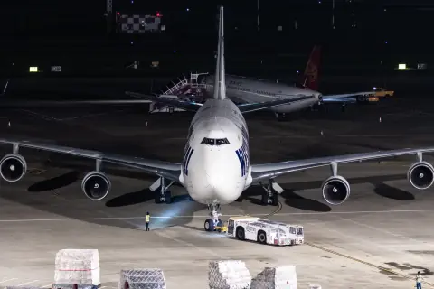 Head-on cargo aircraft with a ground vehicle beneath night apron lights