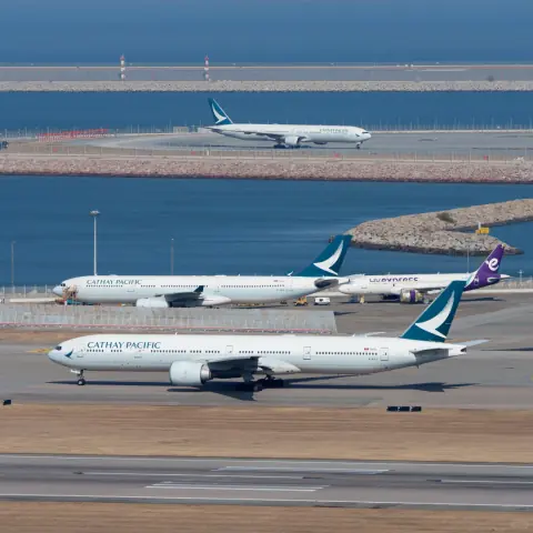 Passenger aircraft taxiing in front of another aircraft at a coastal airport