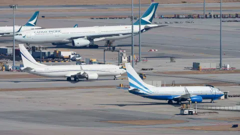 Multiple aircraft arranged across a wide coastal airport apron