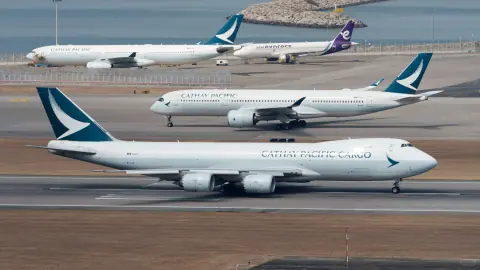 Aircraft and a control tower aligned across a coastal airport apron