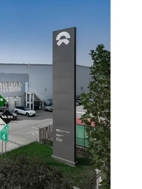 Warehouse entrance and tall wayfinding sign beside landscaped grounds