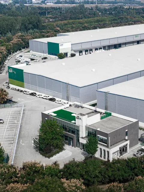Aerial view of white logistics warehouse roofs and a green entrance block