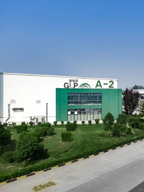 Green and white warehouse entrance behind landscaped planting