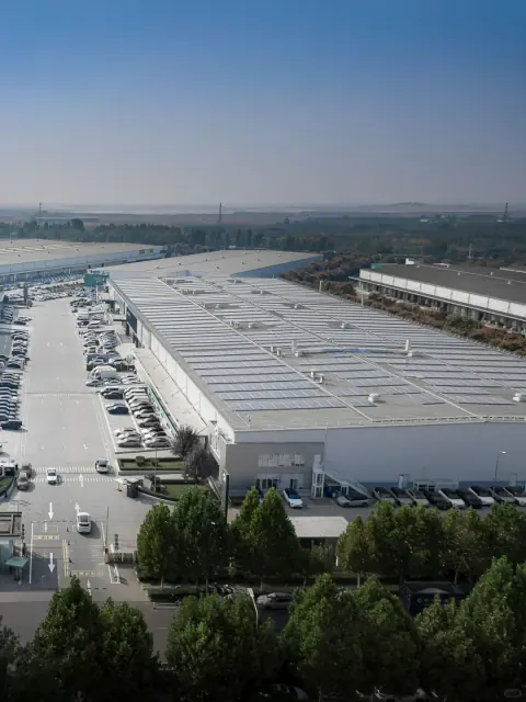 High-angle view along solar-panelled warehouse roofs and an access road