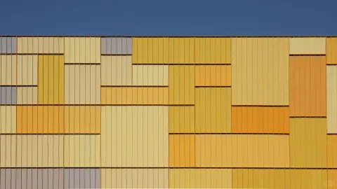 Geometric yellow and grey metal panels on a logistics building