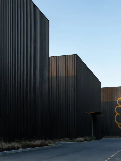 Angular dark metal facades of a logistics centre beneath a blue sky
