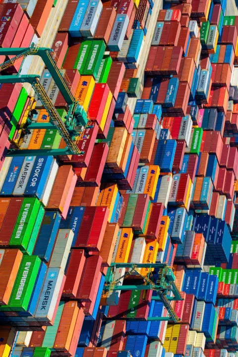 Top-down view of orange gantry cranes over colourful container stacks