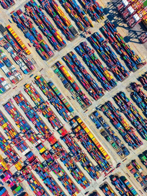 Diagonal rows of colourful containers and gantry cranes at a seaport