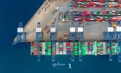 Container quay and colourful terminal stacks beside blue harbour water