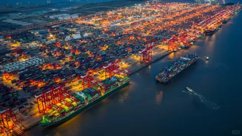 High-angle view of glowing container stacks and a quay at blue hour
