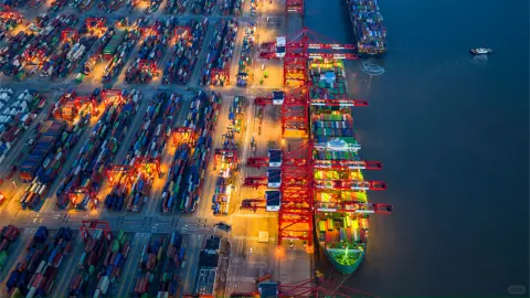 Bright container stacks and a docked ship beside deep blue harbour water