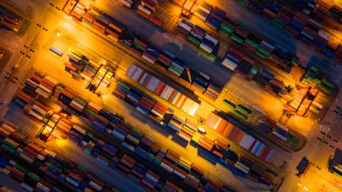 Diagonal aerial view of container stacks under orange terminal lights
