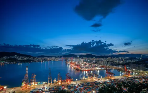 Harbour basin and container terminal beneath a deep blue evening sky