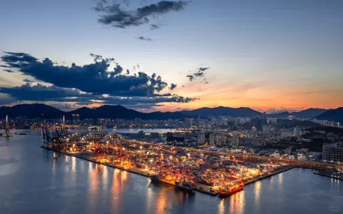 Panoramic harbour and illuminated terminal beneath a sunset sky