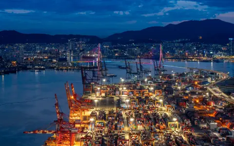 Container terminal cranes and mountain skyline under blue evening light
