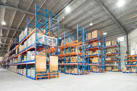 Pallet racks and stacked cartons in a bright high-ceiling warehouse