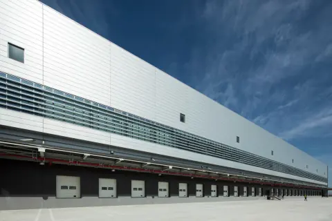 White warehouse facade with a row of covered loading bays