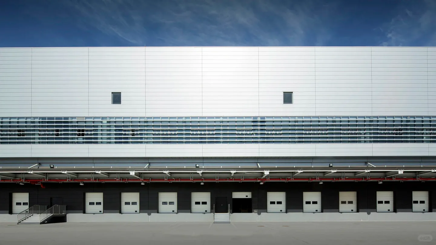 Continuous loading doors along a white industrial warehouse