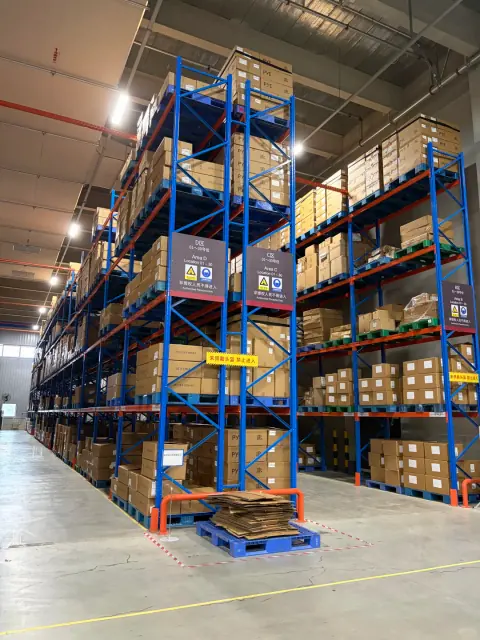 Tall blue and orange storage racks in a working warehouse