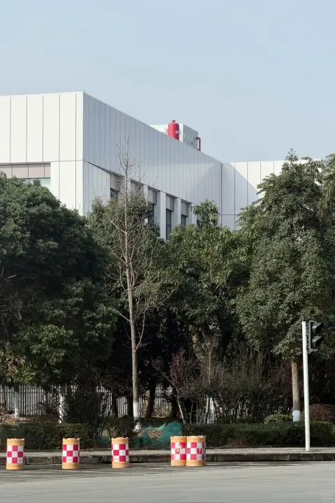 Modern distribution building behind trees and roadside planting