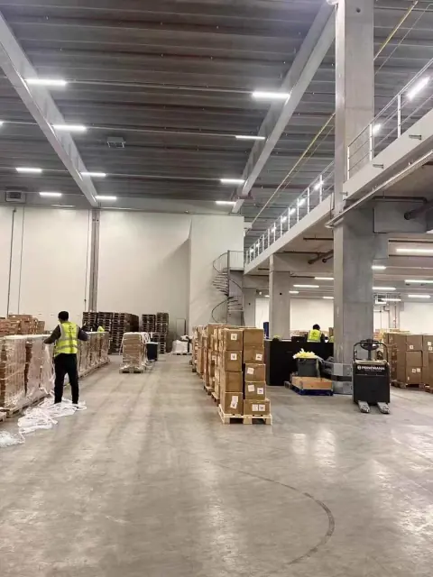 Workers and palletised cartons inside a warehouse hall