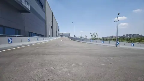 Straight logistics park roadway beside long grey warehouse buildings