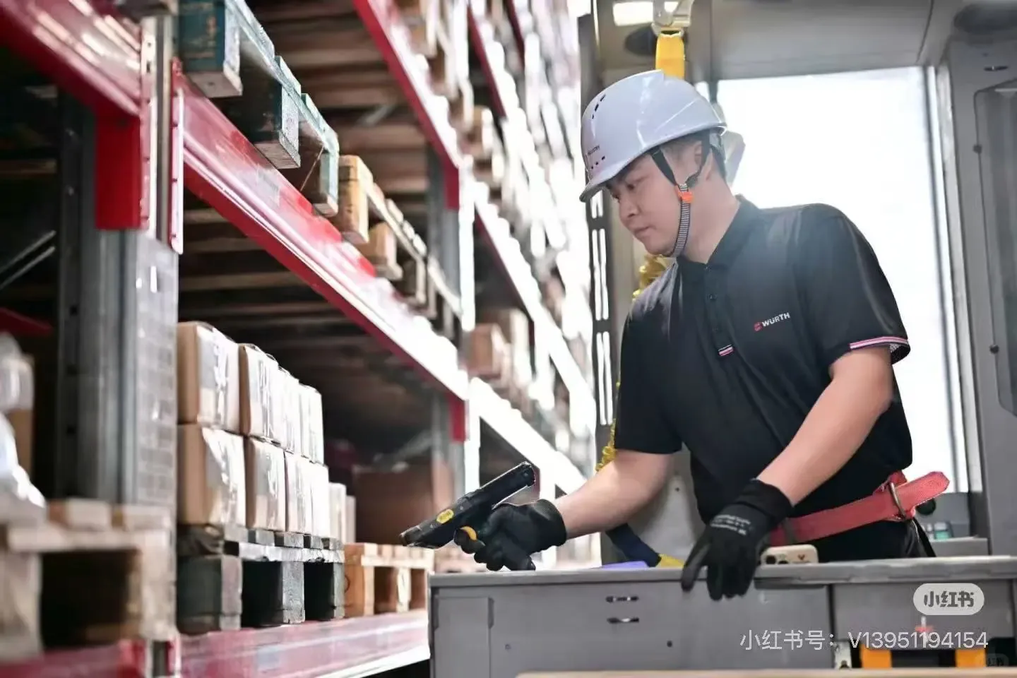 Warehouse worker scanning goods beside a red storage rack